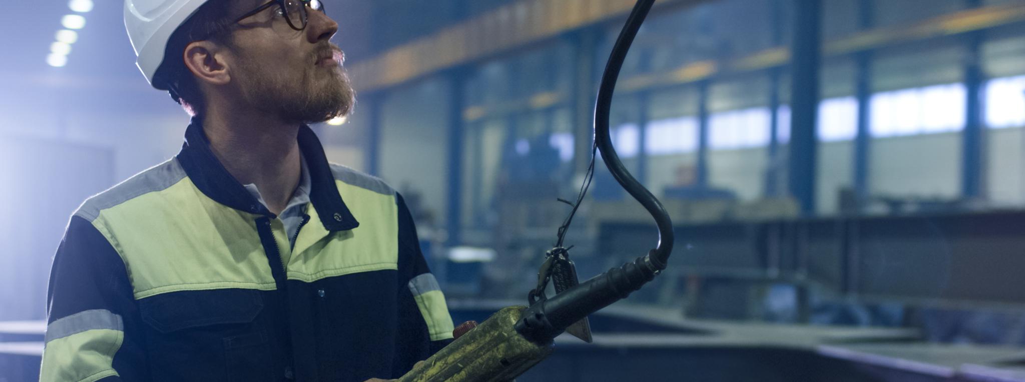 Close-up Shot of a Heavy industry worker at a factory is holding a remote control that operates a crane